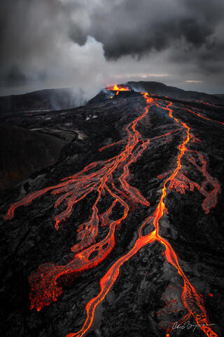 Veins of molten lava are bright orange as they flow down the edge of the active volcano.