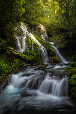 View of a waterfall with two drops as seen from below in the Columbia River Gorge with lush green surroundings.
