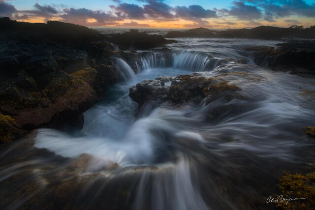 At the volcanic rock shore line water cascades into large holes that fill up with water that then rushes out. 