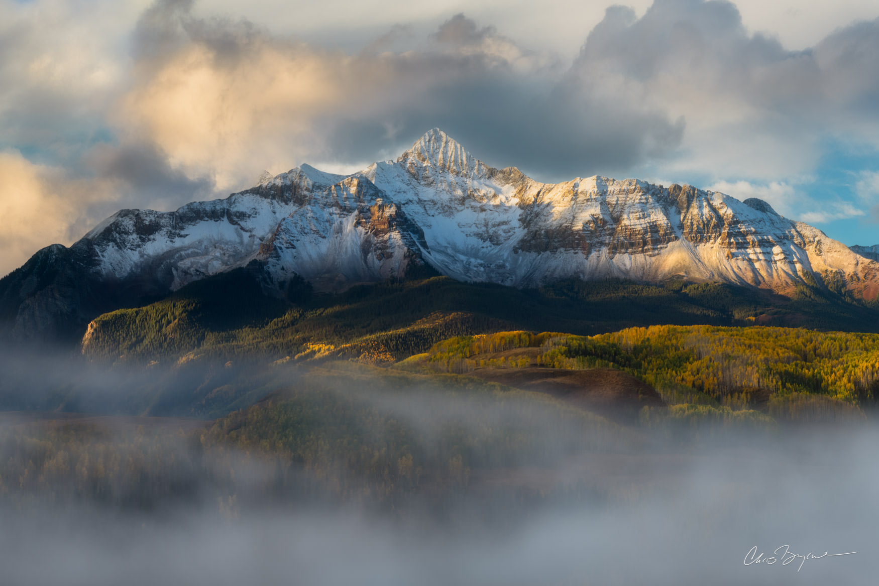 COLORADO DREAM Snow covered mountain landscape photo with yellow leaves on the trees in the valley that are covered in light clouds.