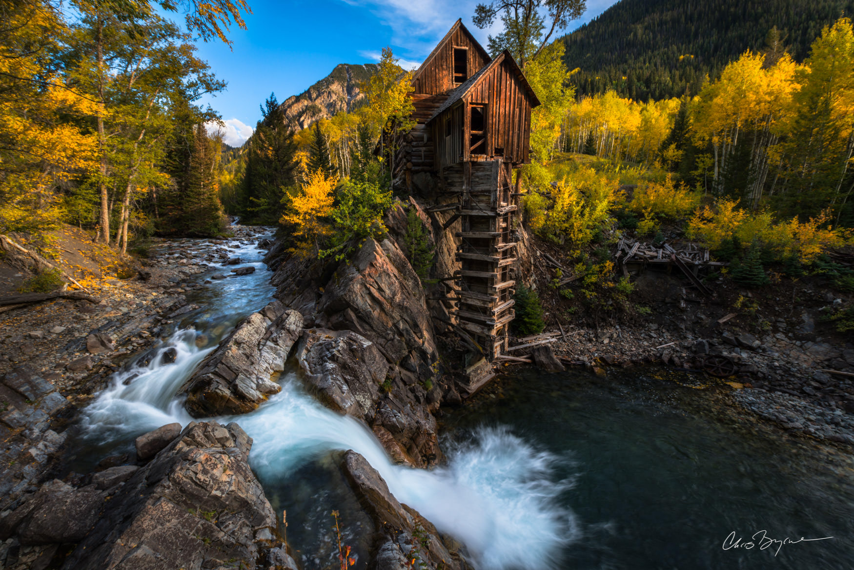 RELIC A rustic old mill sits rests in the backwoods surrounded by yellow leaved aspen trees and a river that flows in and tumbles over the rocks.